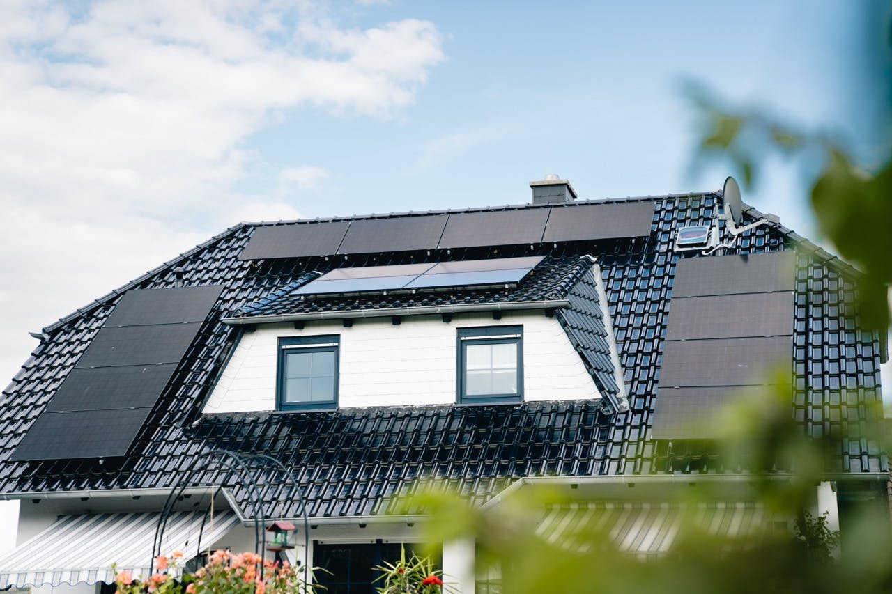 Vitt hus med svart tak och svarta solceller.