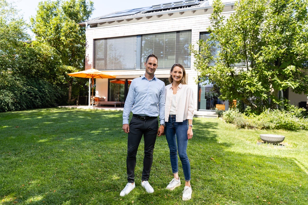 Lyckligt par framför sin villa med solceller