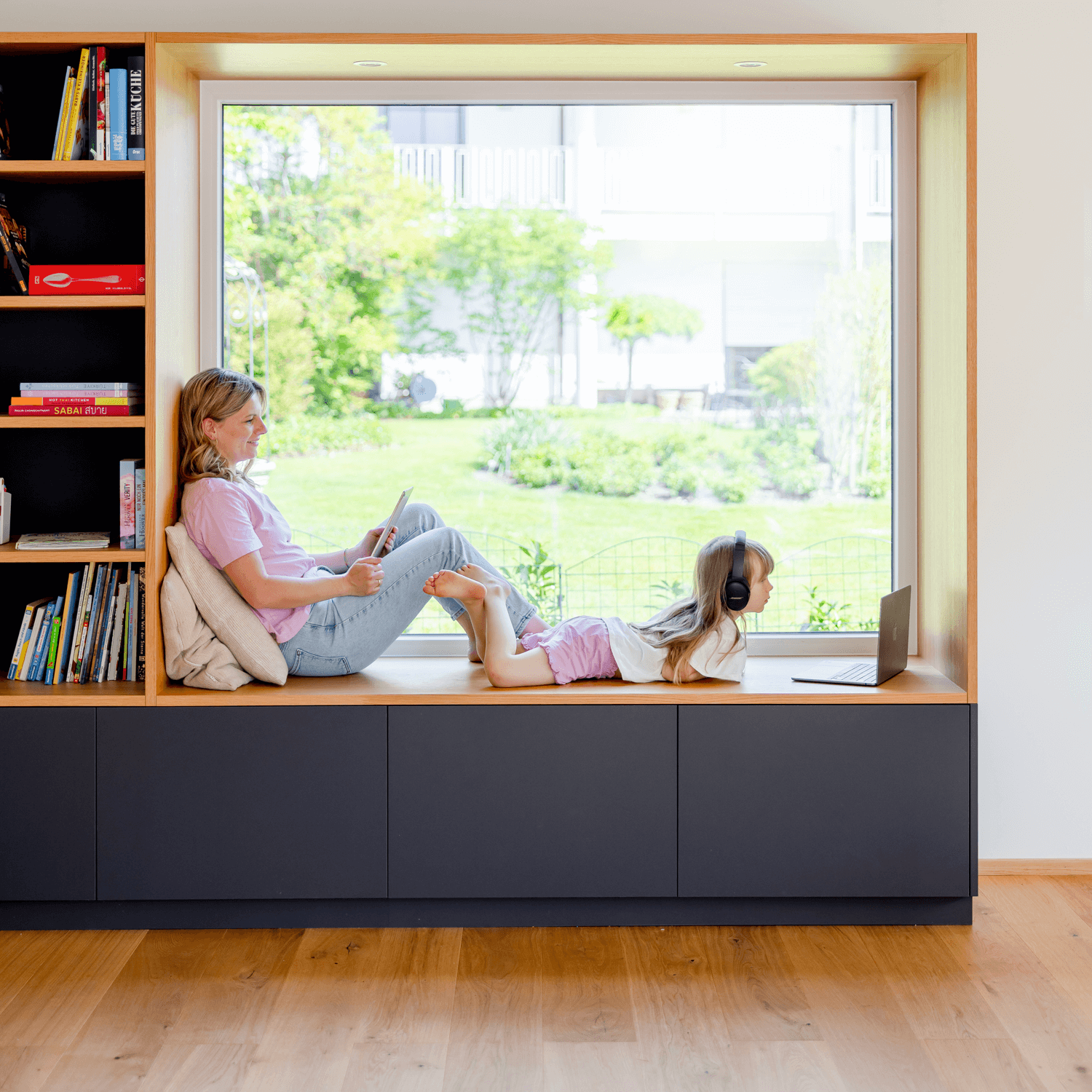 Mamma och dotter vid fönstret i ett varmt vardagsrum