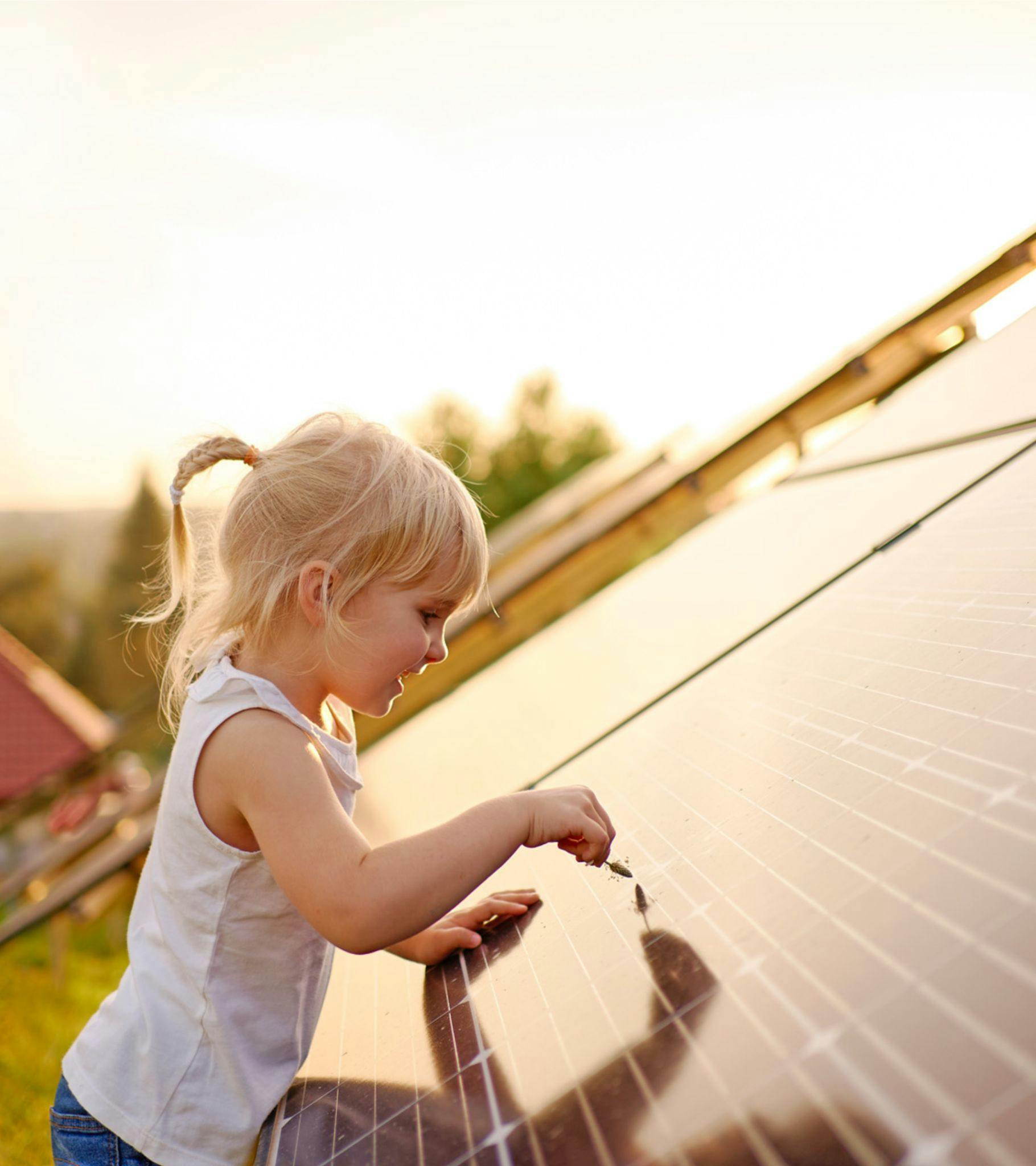 ung flicka vidrör solcellspanel i solnedgången
