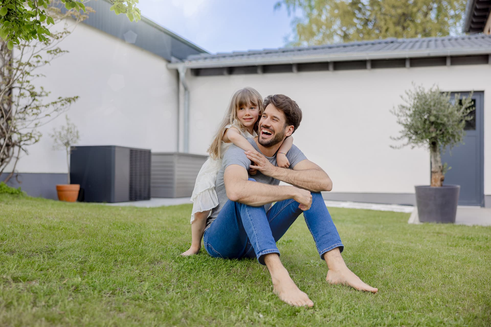Pappa och dotter leker framför värmepumpen på sommaren